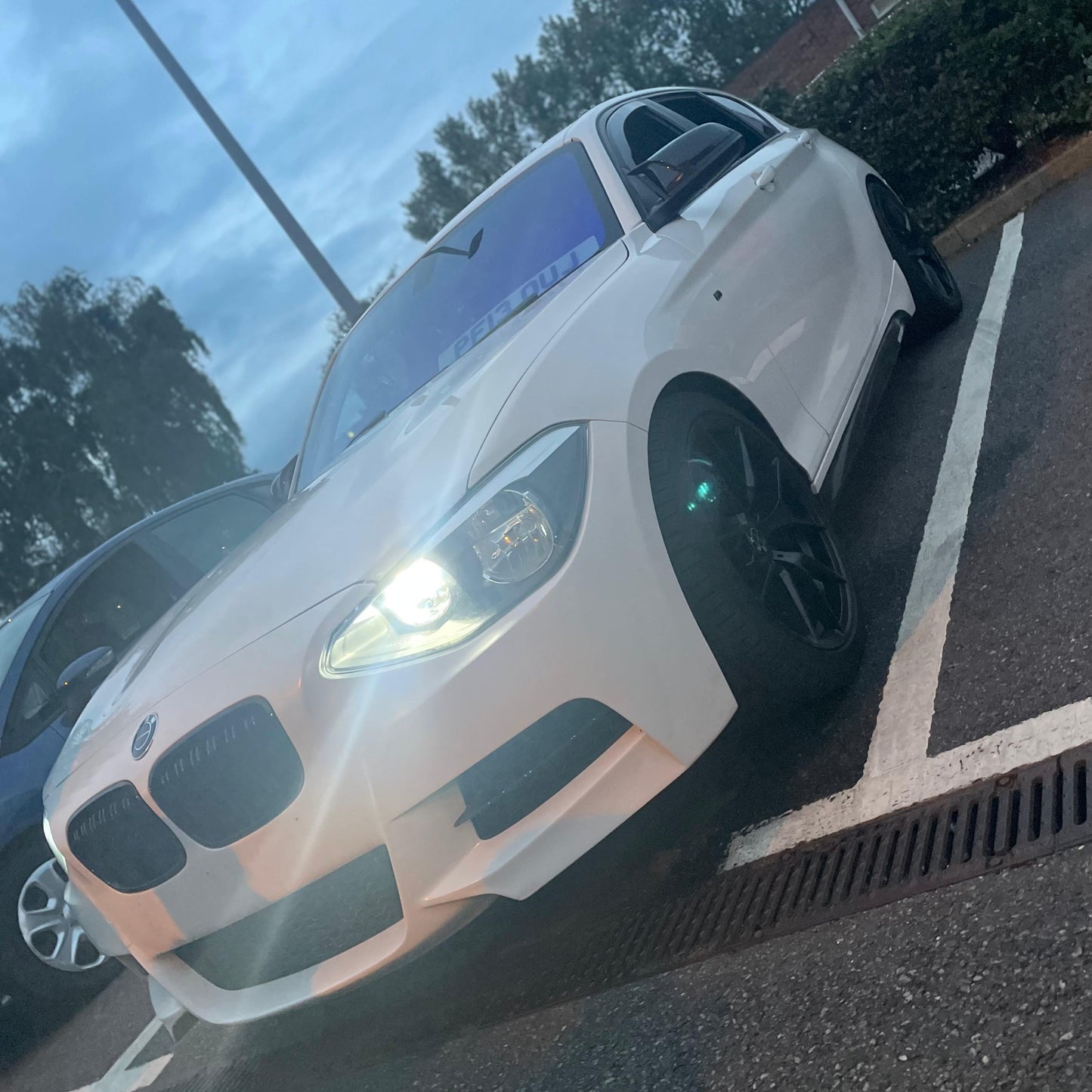White BMW car parked on a street with trees in the background