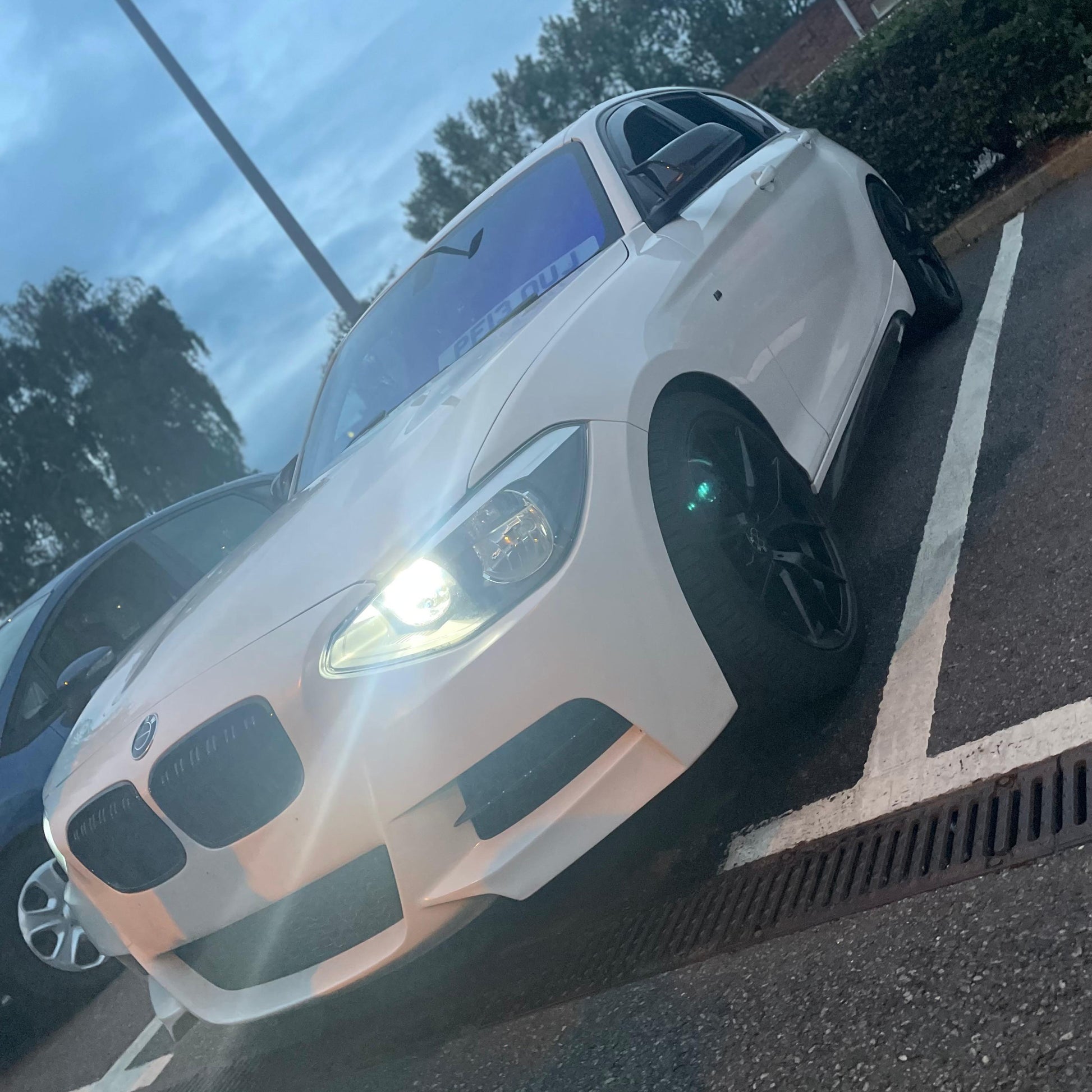 White BMW car parked on a street with trees in the background