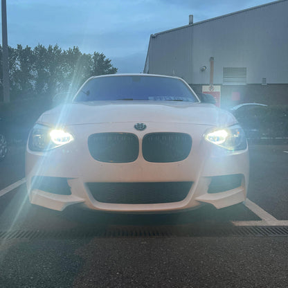 White BMW car in a parking lot with a building and trees in the background